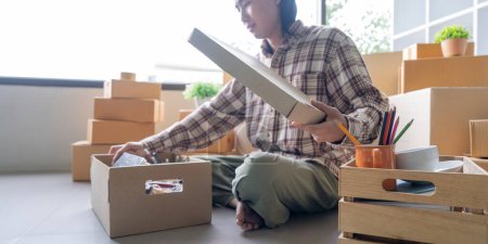 Photo for Concept young man moving house. Asian young man pack cardboard box after moving new house. - Royalty Free Image