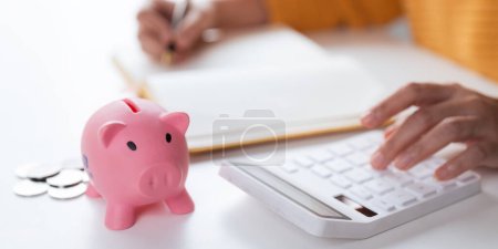 Photo for Businesswomen is keeping a record of his income and expenses, he plans his finances by using his monthly savings to buy funds to make it grow faster. Concept of saving money for investment. - Royalty Free Image