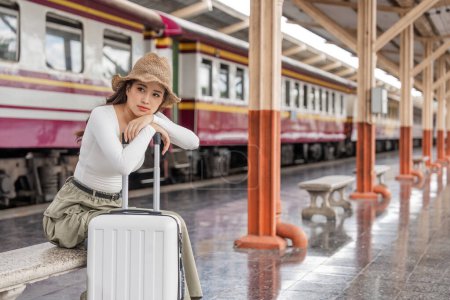 Photo for Young woman asian sitting and waiting for the train waiting for the train to go traveling. Travel concept. - Royalty Free Image