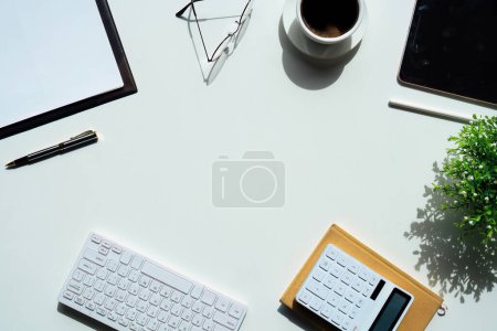 Photo for Top view above of white office desk table with keyboard computer, notebook and coffee cup with equipment other office supplies. business and finance concept. workplace, flat lay with blank copy space. - Royalty Free Image