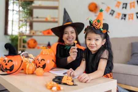 Foto de Mamá asiática y linda hija celebran Halloween y la calabaza globo juntos en casa. Concepto de actividad Halloween. - Imagen libre de derechos