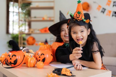 Téléchargez les photos : Maman asiatique et fille mignonne célèbrent Halloween et la citrouille de ballon ensemble à la maison. Concept d'activité Halloween. - en image libre de droit