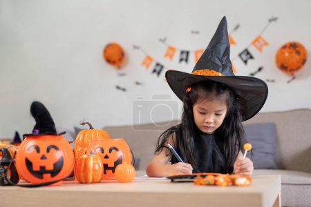 Foto de Concepto de Halloween linda niña pequeña preparándose para celebrar en casa. - Imagen libre de derechos