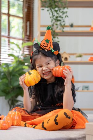 Téléchargez les photos : Petite fille mignonne avec ballon de citrouille. Bonne famille se préparant pour Halloween. - en image libre de droit