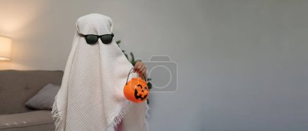 Photo for Funny Halloween Kid Concept, little cute child with white dressed costume halloween ghost scary holding orange pumpkin ghost on hand. - Royalty Free Image
