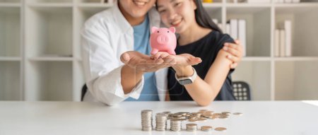Photo for Happy couple asian saving while sitting together on desk at home, loving spouse plan budget and saving money for future. - Royalty Free Image