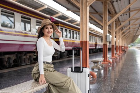 Foto de Mujer joven asiática sentada y esperando el tren esperando a que el tren vaya de viaje. Concepto de viaje. - Imagen libre de derechos