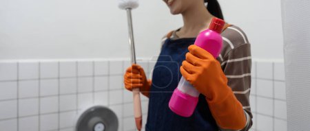 Foto de Una mujer asiática limpiar un baño inodoro con un cepillo de fregar. - Imagen libre de derechos