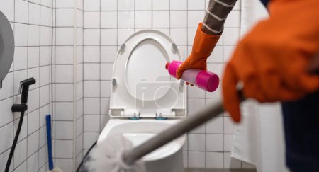 Foto de Una mujer asiática limpiar un baño inodoro con un cepillo de fregar. - Imagen libre de derechos