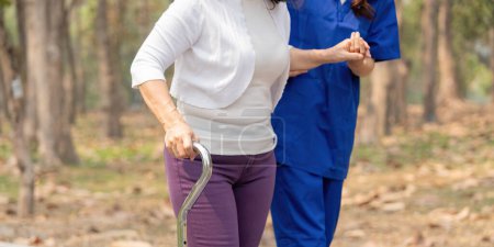 Photo for Nurse and senior in elderly care, support or walking with stick at park. Medical caregiver or therapist help patient or person with a disability in retirement or physiotherapy. - Royalty Free Image