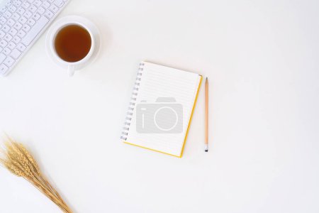 Photo for Top view above of white office desk table with keyboard, notebook and coffee cup with equipment other office supplies. business and lifestyle concept with blank copy space. - Royalty Free Image