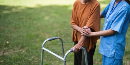 Photo for Nurse or caregiver hand on walking frame for support, help or trust moving leg in rehabilitation. Physiotherapy healthcare, Medical caregiver consulting disabled elderly patient at home. - Royalty Free Image
