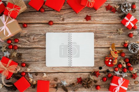 Foto de Mesa de madera y cuaderno por encima del concepto de diseño de fondo de Navidad, composición de adornos de decoración navideña con caja de regalo de Navidad, estrella, renos. - Imagen libre de derechos
