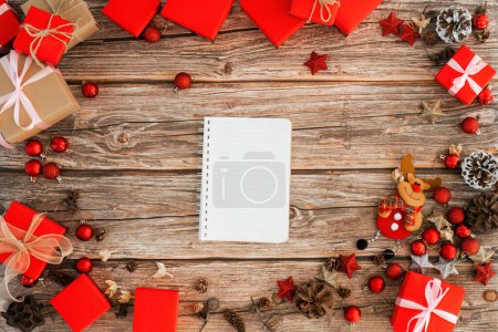 Foto de Mesa de madera y cuaderno por encima del concepto de diseño de fondo de Navidad, composición de adornos de decoración navideña con caja de regalo de Navidad, estrella, renos. - Imagen libre de derechos