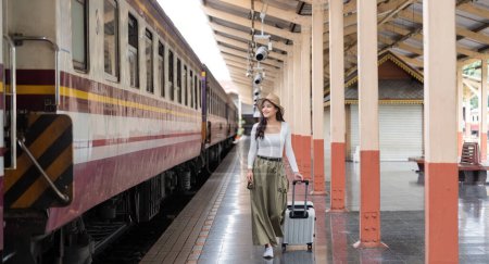 Téléchargez les photos : Seule voyageuse asiatique avec valise dans la plate-forme de la gare. Vacances d'été. - en image libre de droit