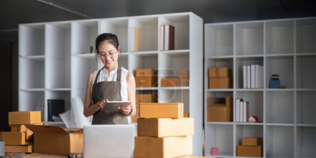 Photo for Startup SME small business entrepreneur of freelance Asian woman using laptop and box to receive and review order online to prepare to pack sell to customers, online sme business ideas. - Royalty Free Image