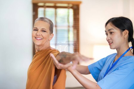 Téléchargez les photos : Physiothérapeute soignante Les femmes âgées asiatiques et caucasiennes font confiance à la main mobile dans la réadaptation. Soins de santé en physiothérapie, consultation d'un soignant âgé handicapé à domicile. - en image libre de droit