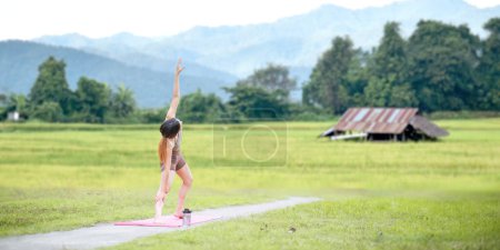 Téléchargez les photos : Femmes en bonne santé faisant du yoga le matin Au milieu d'une rizière. concept activité saine et de plein air. - en image libre de droit