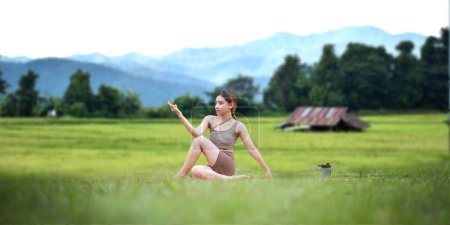 Téléchargez les photos : Femmes en bonne santé faisant du yoga le matin Au milieu d'une rizière. concept activité saine et de plein air. - en image libre de droit