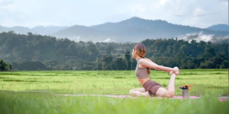 Foto de Mujeres sanas haciendo yoga por la mañana en medio de un campo de arroz. concepto de actividad saludable y al aire libre. - Imagen libre de derechos