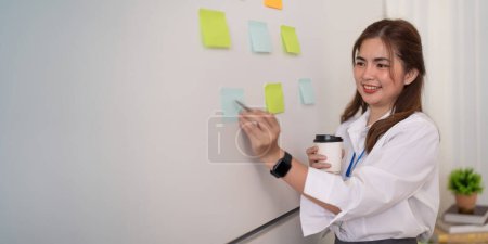 Photo for Businesswoman writing idea or tasks on sticky paper on wall, female team leader, executive manager, planning project, organize work. - Royalty Free Image