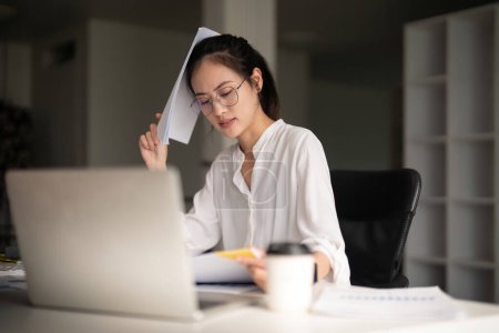 Téléchargez les photos : Femmes asiatiques d'affaires sont le stress tout en travaillant sur un ordinateur portable, Fatigué femme d'affaires avec des maux de tête au bureau, se sentir malade au travail. - en image libre de droit