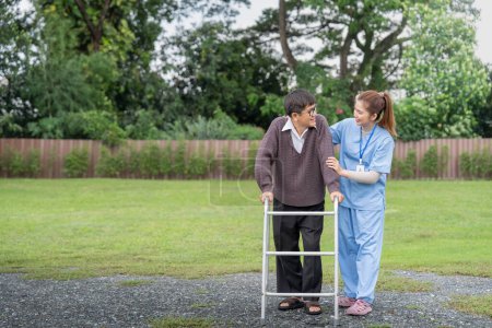 Photo for Asian caregiver nurse support senior older male walk outdoors. Specialist girl doctor help and take care of elderly mature man patient doing physical therapy at home. - Royalty Free Image