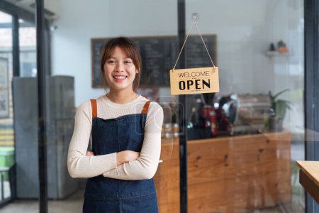 Téléchargez les photos : Femme asiatique barista tenant tablette pour vérifier la commande du client sur fond de café café flou, concept d'entreprise PME. - en image libre de droit