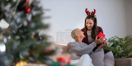 Photo for Caucasian Family, winter holiday and concept happy mother and daughter decorating christmas tree and give a gift at home. - Royalty Free Image