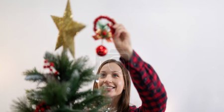 Téléchargez les photos : Femme gaie décorer l'arbre de Noël. Ambiance de Noël à l'intérieur confortable maison. - en image libre de droit