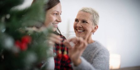 Téléchargez les photos : Vacances d'hiver en famille et concept heureuse femme âgée avec fille adulte décorer arbre de Noël à la maison. - en image libre de droit