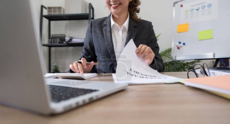 Téléchargez les photos : Femme d'affaires comptable à l'aide d'une calculatrice et d'un ordinateur portable pour l'épargne de données financières dans la salle de bureau, Financière d'entreprise, fiscalité, concept comptable. - en image libre de droit