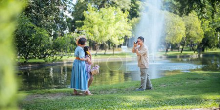 Photo for Grandpa takes pictures of granddaughter and grandma with his in park on sunny day happiness. concept grandparent and grandchild family lives together happy. - Royalty Free Image