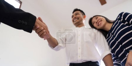 Téléchargez les photos : Couple asiatique poignée de main avec un agent immobilier après l'achat d'une maison. - en image libre de droit