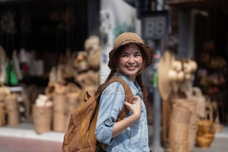 Foto de Mujer hermosa joven que viaja en el mercado local durante las vacaciones. Las mujeres turísticas viajan en Chiang mai disfrutan del mercado de compras durante las vacaciones, viajero mochilero. - Imagen libre de derechos