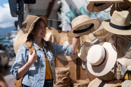 Photo for Happy young woman asian is visit local market during her trip and purchase straw hat handmade. Tourist women travel in Chiang mai enjoy shopping market during holidays, backpacker traveller. - Royalty Free Image