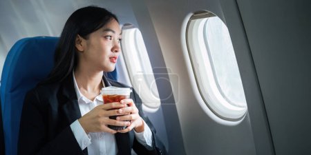 Téléchargez les photos : Succès asiatique femme d'affaires, Femme d'affaires travaillant dans l'avion sur ordinateur portable et regardant par la fenêtre. - en image libre de droit
