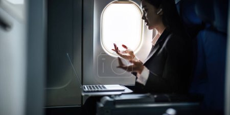Foto de Exitosa mujer de negocios asiática, mujer de negocios que trabaja en cabina de avión durante el vuelo en el ordenador portátil. - Imagen libre de derechos