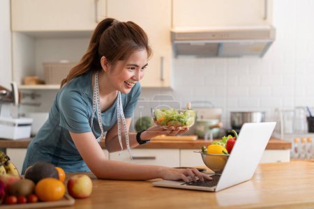 Photo for Young woman eat healthy food sitting in the kitchen. - Royalty Free Image