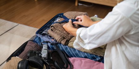 Téléchargez les photos : Beauté asiatique voyageur femme pack préparer des trucs et vêtements de tenue dans valise sac de voyage bagages pour l'été, vacances, week-end, tour, voyage, voyage de vacances à la maison. - en image libre de droit