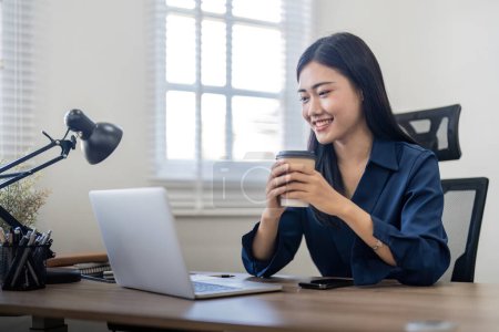 Photo for Smiling woman sitting at her desk in office and coffee. Happy business woman sitting in office. - Royalty Free Image