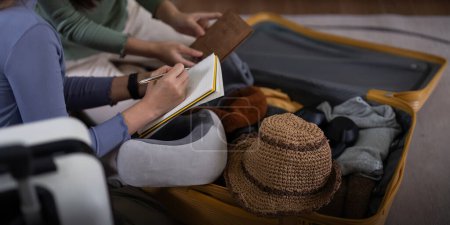 Foto de Dos amigas se preparan para empacar ropa lugares de viaje con sus amigos empacan cosas en su bolsa de viaje para las vacaciones para su viaje de vacaciones. - Imagen libre de derechos