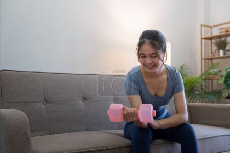 Foto de Joven mujer asiática ejercicio con mancuernas en casa. - Imagen libre de derechos