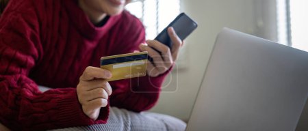 Téléchargez les photos : Jeune femme asiatique mains tenant carte de crédit et en utilisant un smartphone pour l'achat sur Internet. Achats en ligne, Paiement en ligne à domicile. - en image libre de droit