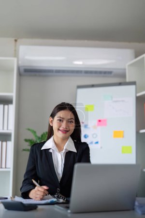 Foto de Retrato de joven mujer de negocios asiática feliz y exitosa empleada en la oficina moderna. - Imagen libre de derechos