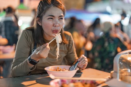 Foto de Viajero mujer asiática disfrutar de comer fideos en el mercado nocturno. tradicional Chiang Mai Tailandia comida callejera.. - Imagen libre de derechos