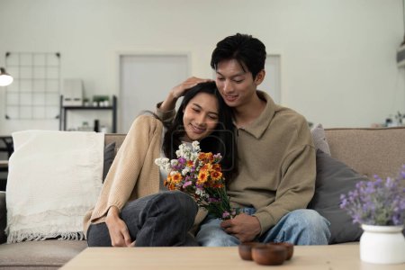 Photo for Asian handsome man show the love and give flowers to his girlfriend in living room on valentine day. Lifestyle Concept. - Royalty Free Image