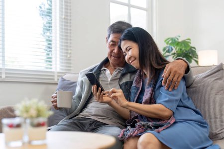 Photo for Portrait of Asian adorable senior couple using smartphone together video chatting with family in living room at home.. - Royalty Free Image