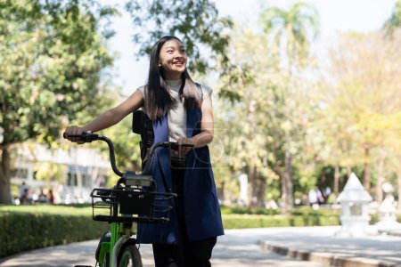 Asiatische Geschäftsfrau mit dem Fahrrad zur Arbeit im Büro. Fahrradpendler, glückliche Geschäftsfrau mit Ökotransport, Konzept des Öko-Lebensstils.