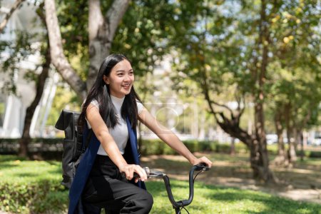Téléchargez les photos : Femme d'affaires asiatique en vélo aller travailler au bureau. Voyager à vélo, femme d'affaires heureuse utilisant les transports écologiques, Concept de mode de vie écologique. - en image libre de droit